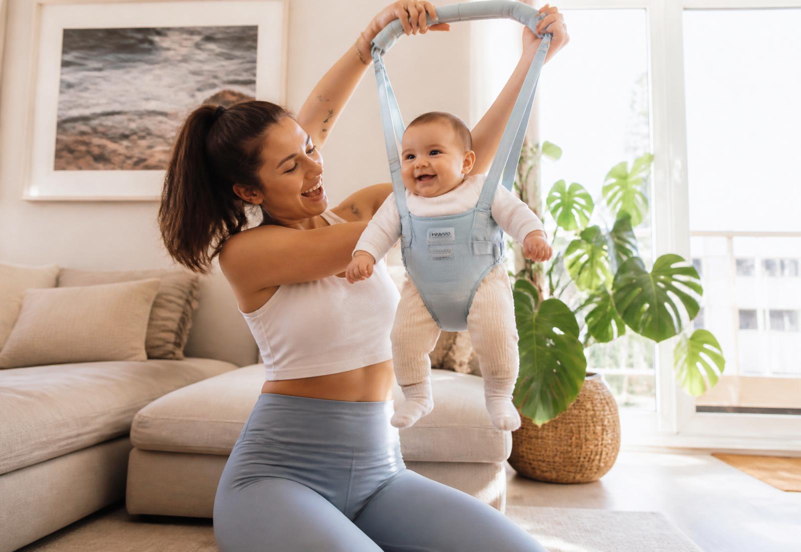 Parent lifting a smiling baby in a LittleLifts padded harness
